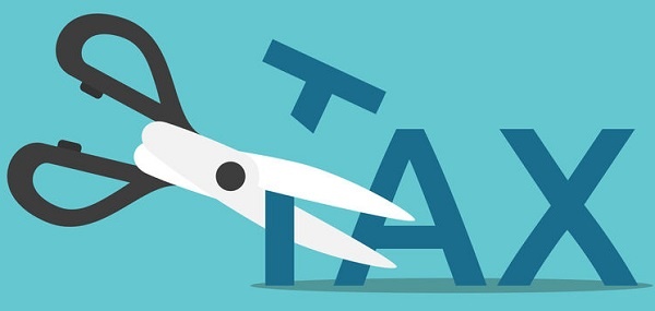Tax Deduction- Tax Saving Scissors cutting word tax on blue background
