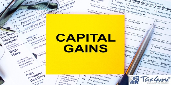 Text Capital Gains on note paper with the U.S IRS 1040 form, pen and glasses